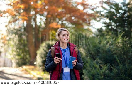 Woman Caregiver, Nurse Or Healthcare Worker Outdoors On The Way To Work, Using Smartphone.