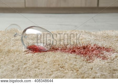 Overturned Glass And Spilled Red Wine On Soft Carpet
