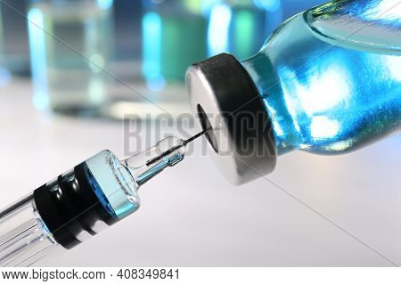 Filling Syringe With Vaccine From Vial On Blurred Background, Closeup