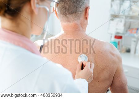 Doctor using stethoscope to check lung function on back of man