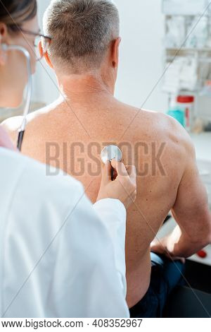 Doctor using stethoscope to check lung function on back of man