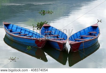 Colourful Bright Blue Rowing Boats On Tranquil Phewa Lake, Pokhara, Nepal With Clouds Reflected In W