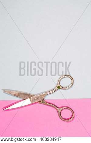 Pair Of Old Used Metal Rusty Scissors Placed Over Pink And Blue Paper Background.