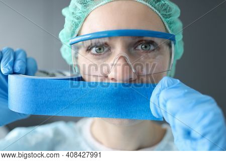 Woman Doctor Sealing Her Mouth With Blue Tape. Medical Secrecy Concept