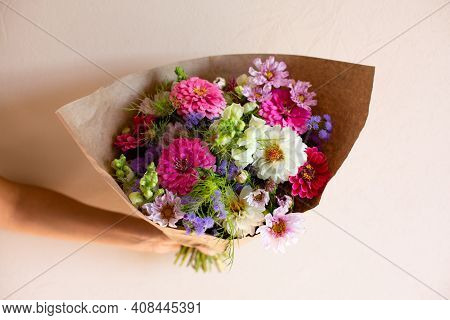 Hand With Beautiful Bouquet Of Seasonal Flowers On Pink Background. Pink Zinnia, White Dahlia, Cosmo