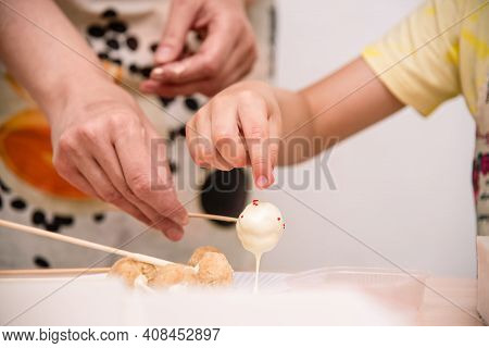 Mom And Child Together Themselves Cooking Of Cake-pops. The Mother Holds The Popcake On A Stick, The