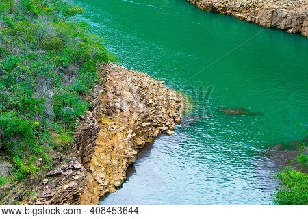 Lake With Natural Green Water Surrounded By Sedimentary Rocks On Lake Shore And Green Vegetation. Ph