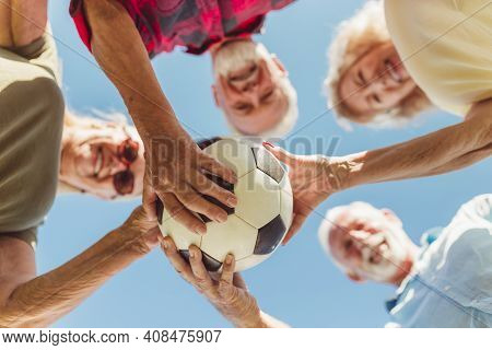 Low Angle View Of A Group Of Cheerful Active Senior People Having Fun Playing Football, Gathered In 