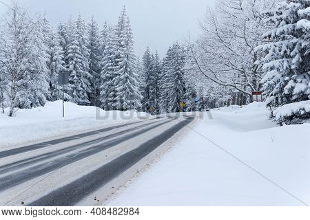Jizera Mountains In Poland. Asphalt Road Covered With Broken Snow. Black Ruts. It Is The Provincial 