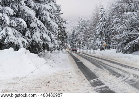 Jizera Mountains In Poland. Asphalt Road Covered With Broken Snow. Black Ruts. It Is The Provincial 