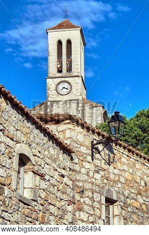 Stone Houses And Belfry With Clock In Village Of Balazuc In France