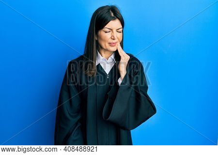 Young hispanic woman wearing judge uniform touching mouth with hand with painful expression because of toothache or dental illness on teeth. dentist 