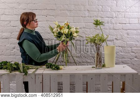 Florist Workplace On The Light Background. The Florist Creates A Floral Arrangement Of Roses, Lilacs