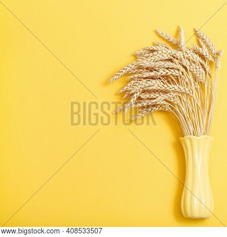 Bunch Of Compressed Stems With Ears. Golden Wheat In Yellow Colored Vase On Monochrome Background. W