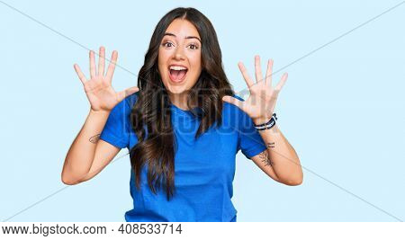 Beautiful brunette young woman wearing casual clothes showing and pointing up with fingers number ten while smiling confident and happy. 