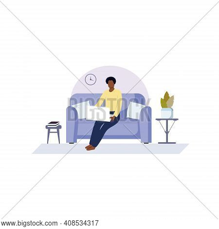 An African-american Man Is Sitting On A Sofa And Working On A Computer. A Black Man Works At Home On