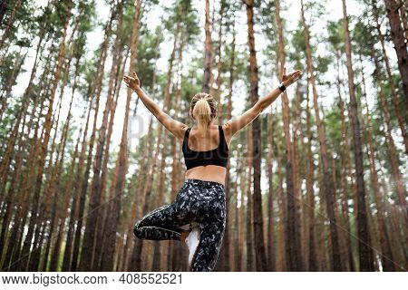 Beautiful Woman Standing And Doing Yoga In Forest. Exercise And Meditation Concept. Pay Obeisance Or