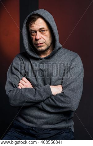 Studio Portrait Of A 40-50-year-old Serious Man In A Gray Hoodie On A Neutral Background, Eyes Direc