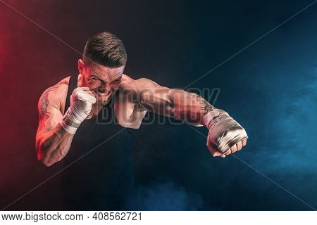 Bearded Tattooed Portsman Muay Thai Boxer In Black Undershirt And Boxing Gloves Fighting On Dark Bac