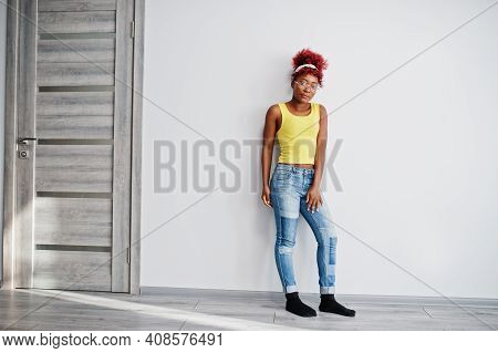 African American Woman In Yellow Singlet And Eyglasses Against White Wall.
