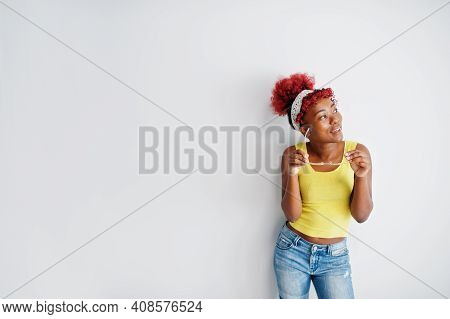 African American Woman In Yellow Singlet And Eyglasses Against White Wall.