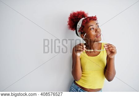African American Woman In Yellow Singlet And Eyglasses Against White Wall.