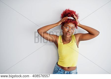 African American Woman In Yellow Singlet And Eyglasses Against White Wall.