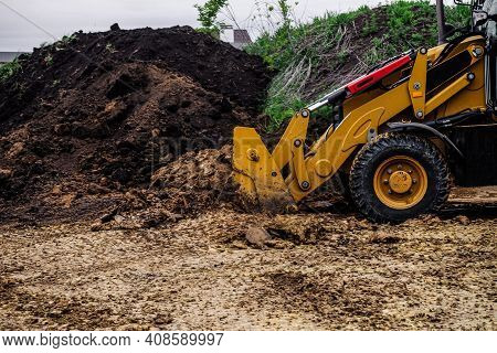 Backhoe Loader Planning And Cutting Clay Ground At Eathmoving Works In Construction Site