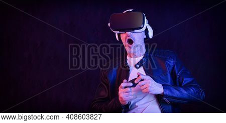 Modern Adult Man Interacting With Virtual Reality Glasses Controlling With A Joystic With Dark Isola