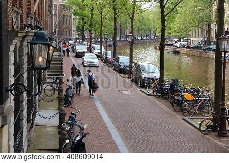 Amsterdam, Netherlands - July 10, 2017: People Stroll Along Herengracht Canal In Amsterdam City, Net