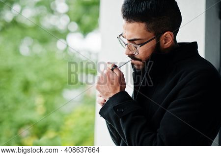 Middle Eastern Entrepreneur Wear Black Coat And Blue Shirt, Eyeglasses Against Office Building Smoki