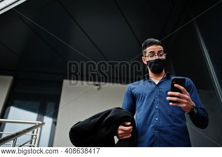 Middle Eastern Entrepreneur Wear Black Face Mask And Eyeglasses Look At Mobile Phone. New Normal Lif