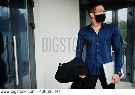 Middle Eastern Entrepreneur Wear Black Face Mask And Eyeglasses Hold Laptop. New Normal Life After C