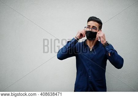 Middle Eastern Entrepreneur Wear Black Face Mask And Eyeglasses Against White Wall. New Normal Life