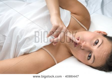 Attraente giovane donna a letto dicendo Shhhhh.