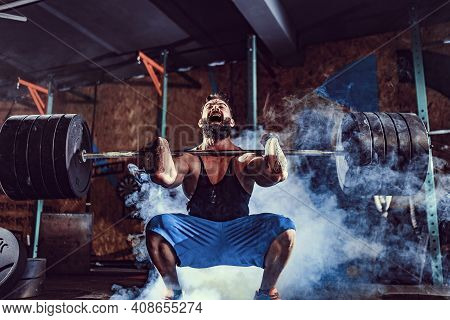 Muscular Bearded Tattoed Fitness Man Doing Deadlift A Barbell Over His Head In Modern Fitness Center
