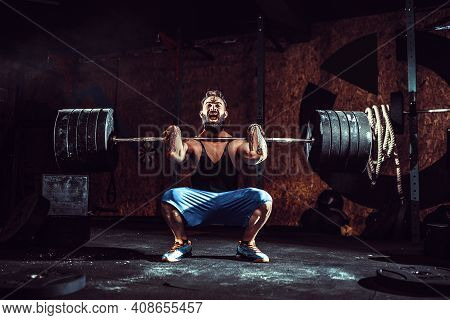 Muscular Bearded Tattoed Fitness Man Doing Deadlift A Barbell Over His Head In Modern Fitness Center