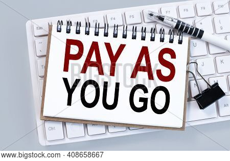 Pay As You Go. Text On White Notepad Paper On White Keyboard On Gray Background
