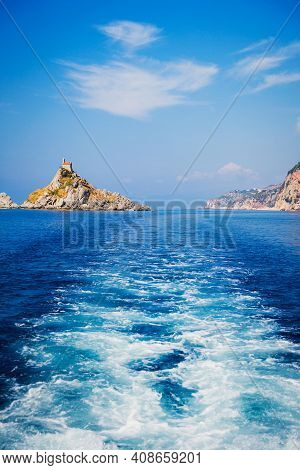Wave Trace Tails Of Speed Boat On Blue Water Surface In The Sea. View On Grey Rock Islend. Budva Riv