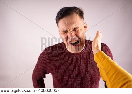 Crop Person Slapping Scared Man In Face. Emotional Male Getting Slapped In Face While Shouting With