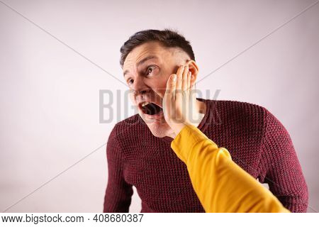 Crop Person Slapping Scared Man In Face. Emotional Male Getting Slapped In Face While Shouting With