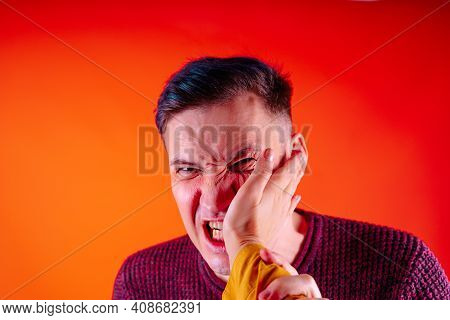 Man Getting Slapped On Orange Background. Unhappy Scared Man Getting Slapped Standing On Orange Back