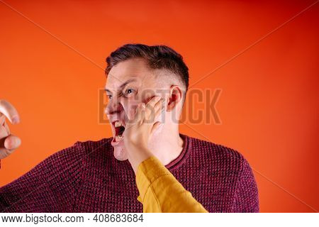 Man Getting Slapped On Orange Background. Unhappy Scared Man Getting Slapped Standing On Orange Back