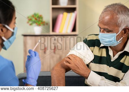 After Doctor Giving Vaccination Shot To Elderly Patient By Syringe Or Injunction, Patient Rubbing Hi