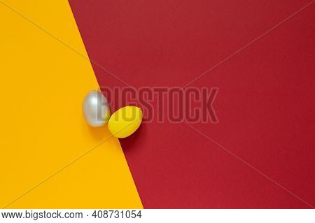 Two Colored Painted Eggs On Colored Yellow And Red Background Easter Card With Empty Space For Text.