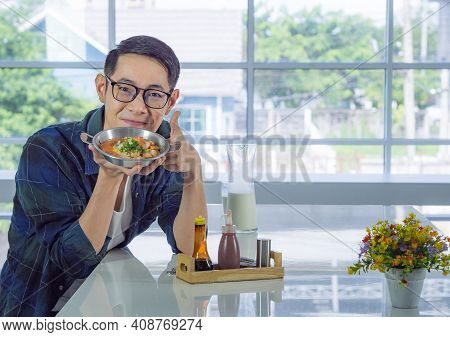 Young Man Wearing Glasses Holding The Fried Egg Served On A Pan With Colorful Toppings Served On A P