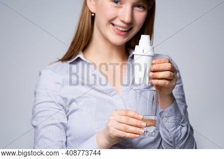 The Womans Hand With A Glass Of Purified Water. The Concept Of Water Purification Through The Minera