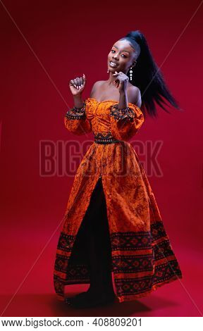 Beautiful Happy African Woman In Traditional Dress Dancing On Red Background, Studio Shot