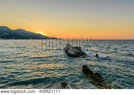 Beautiful Sunset On The Sea. Picturesque Rock In The Sea At Sunset, Kokkari Beach, Samos Island, Gre