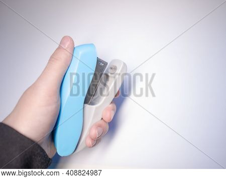 A Blue Paper Stapler Is Held In Your Hand. Blue Stapler Of The Paper. Stapler In Hand.